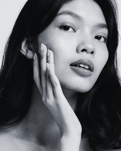 Black and white portrait of a woman with one hand on her face.