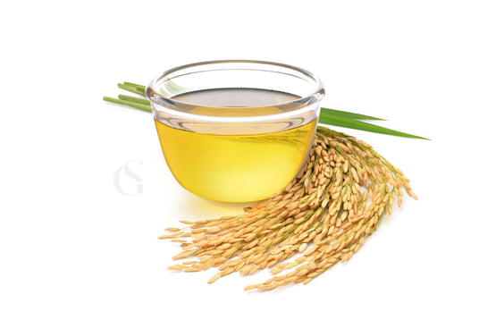 small glass bowl in center containing pale golden liquid with amber rice grains still attached to the stalk wrapped around the base of the bowl on the right