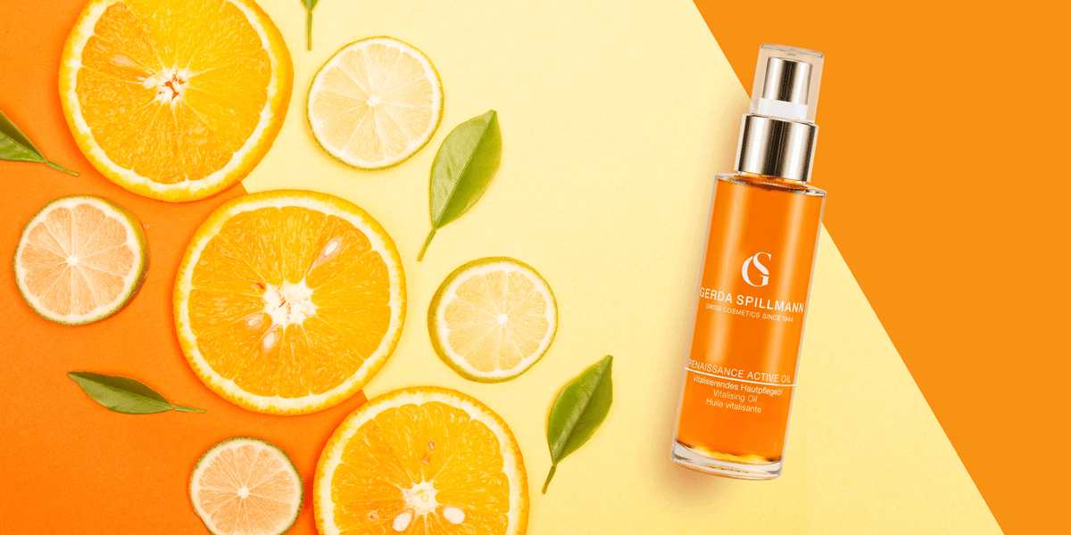 orange and lemon slices in a pattern on the left with leaves, orange and silver cylindrical pump bottle to the right with a striped orange and yellow background