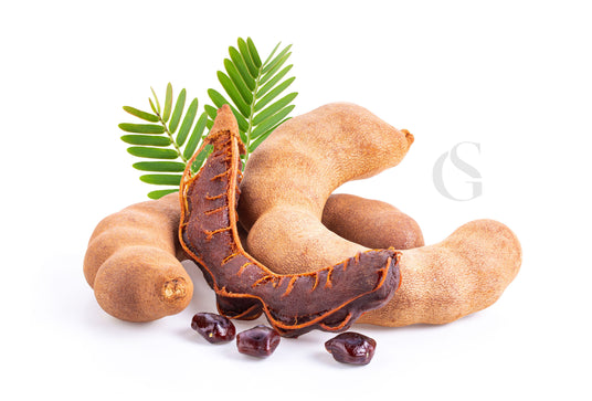 curved, brown seed pods with exposed darker brown pod between and with seeds in front; green leaves behind pods and a white background