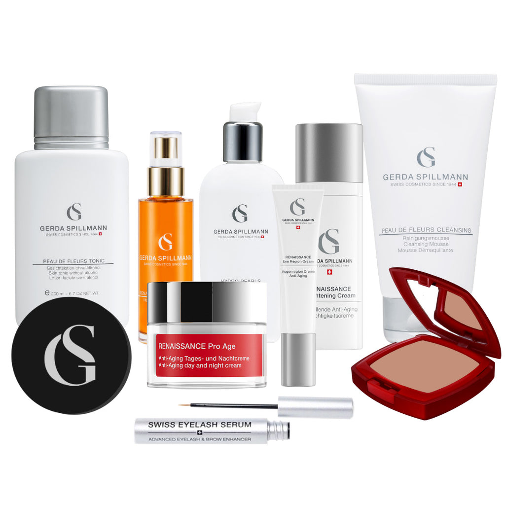 group photo of skincare products in various containers with the GS logo, mostly white and silver with an orange oil in the back, black circular container to the bottom left and red square compact on the bottom right