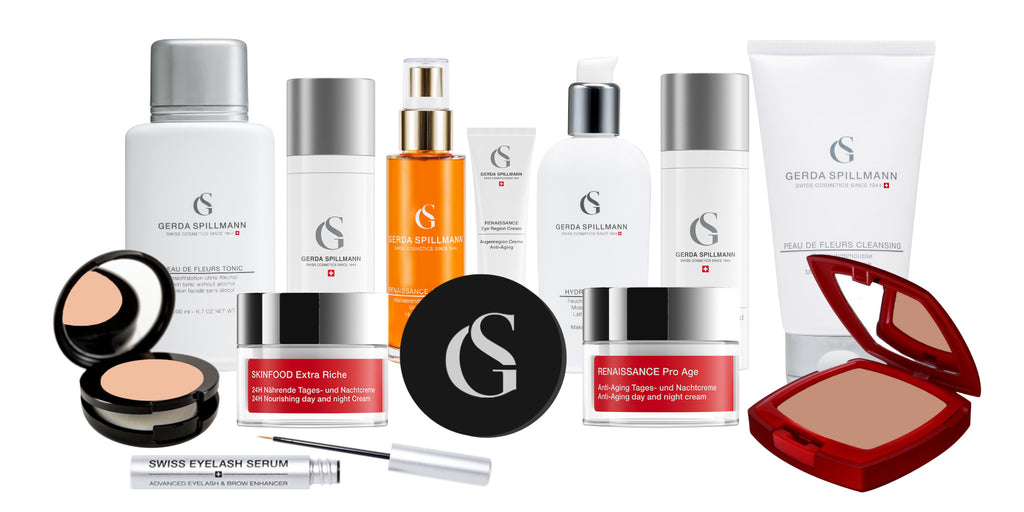 variety of skincare products in a front and back row with the GS logo; front includes black round compact in the right front, and red square compact in left front