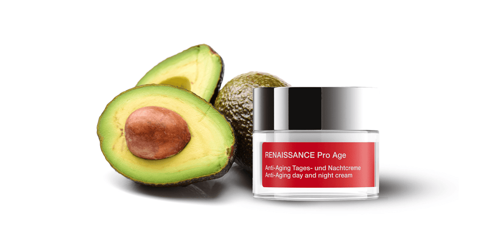 halved avocado, whole avocado to the left of a cylindrical jar with dark silver lid and red rectangular label 