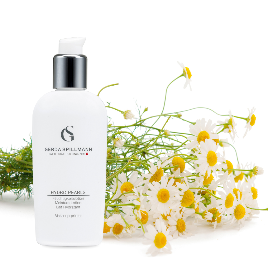 White Hydro Pearls skincare bottle with silver cap on a white background with greenery and flowers.